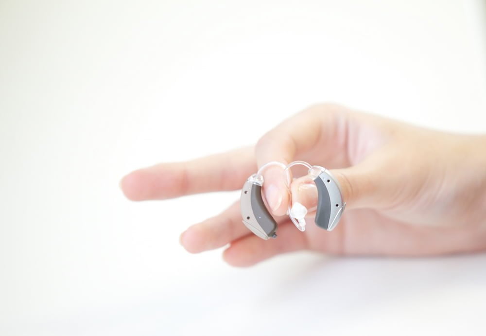 Closeup of hand holding hearing aids with domes
