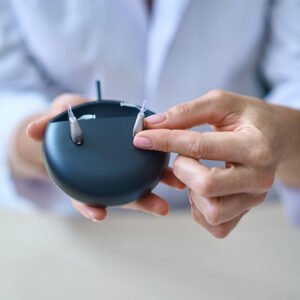 Hearing aid dispenser holding a hearing aid case/charger with a pair of hearing aids inside