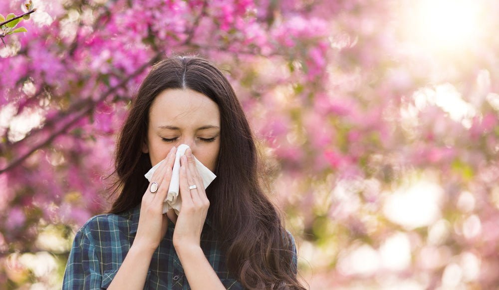 Young woman in park experiencing spring allergy symptoms