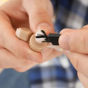 Extreme closeup of hands cleaning hearing aids with a specialised brush